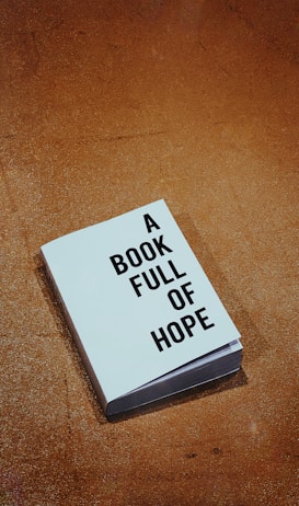 A single book with a cover displaying the words 'A Book Full of Hope' lies on a textured brown surface.