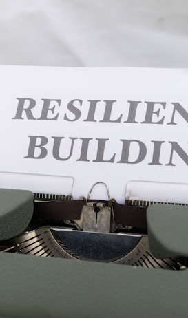 A vintage typewriter holds a sheet of paper with the words 'RESILIENCE BUILDING' typed in bold font.